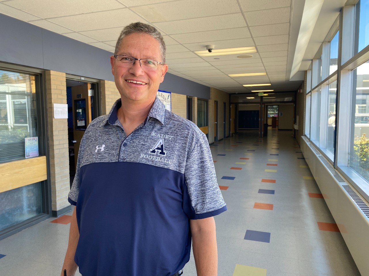 Tim Clark, building manager at Air Academy High School smiles for a picture in the school hallway
